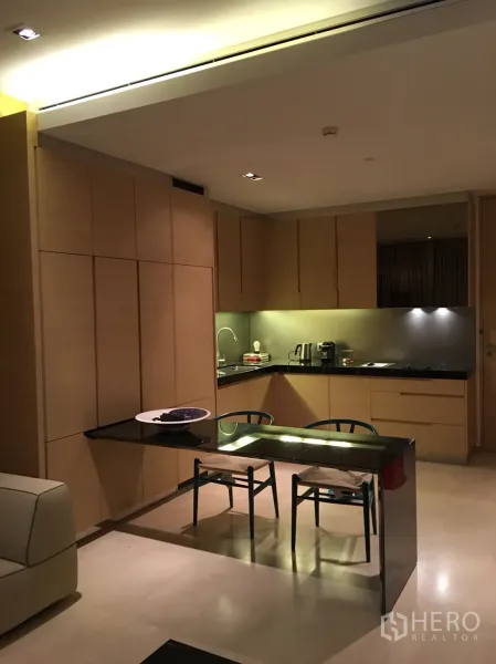 公寓 出租或出售在Bang Rak, Bangkok - 开放式厨房，浅木柜体、黑色石材台面与双人餐桌相连。