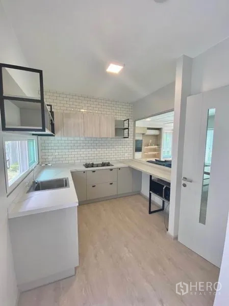 联排别墅 出租在Prawet, Bangkok - U形厨房，白色台面、地铁砖挡水板与燃气灶