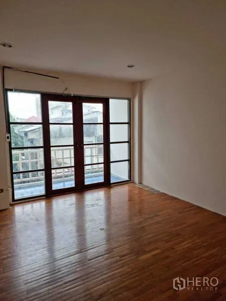 ทาวน์เฮาส์ ให้เช่าในWang Thonglang, Bangkok - ห้องนอนผนังสีอ่อน พื้นไม้ และประตูกระจกออกระเบียง