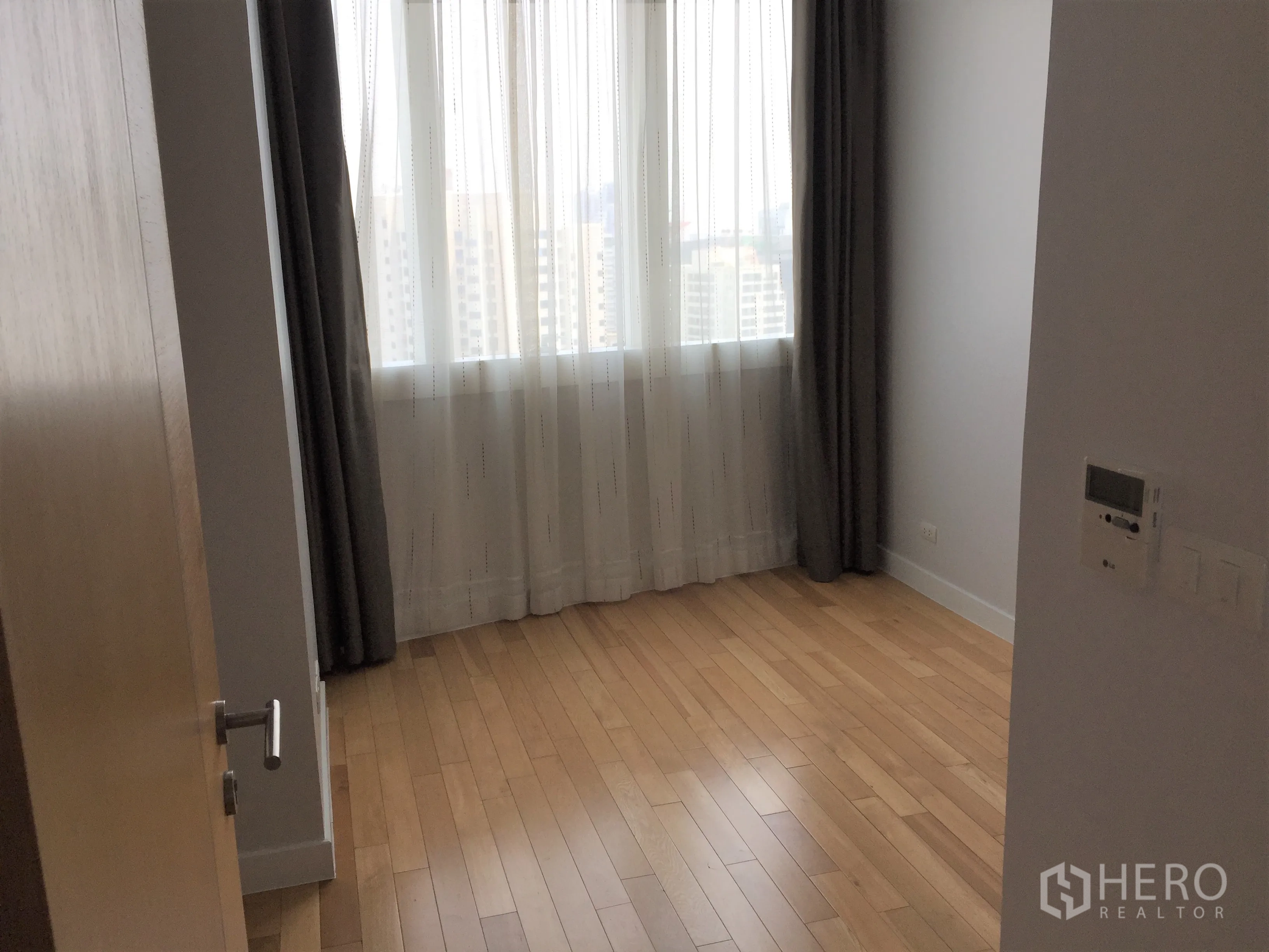 คอนโด ให้เช่าในKhlong Toei, Bangkok - ห้องนอนพร้อมหน้าต่างบานใหญ่ วิวเมือง และพื้นไม้โทนอุ่น.