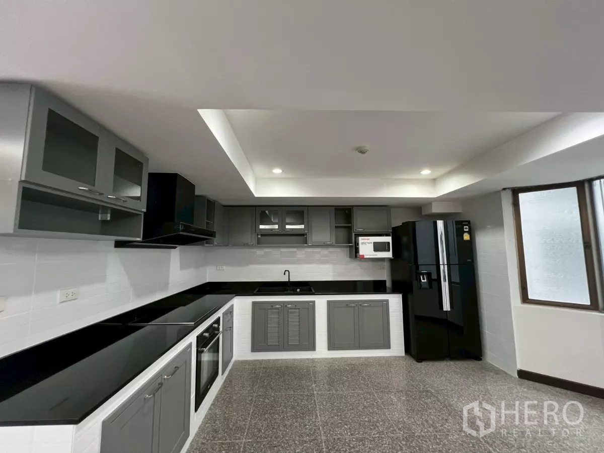 คอนโด ให้เช่าในWatthana, Bangkok - ครัวรูปตัว U โทนเทา เคาน์เตอร์สีดำ มีเตาอบ เตาไฟฟ้า และตู้เย็นขนาดใหญ่