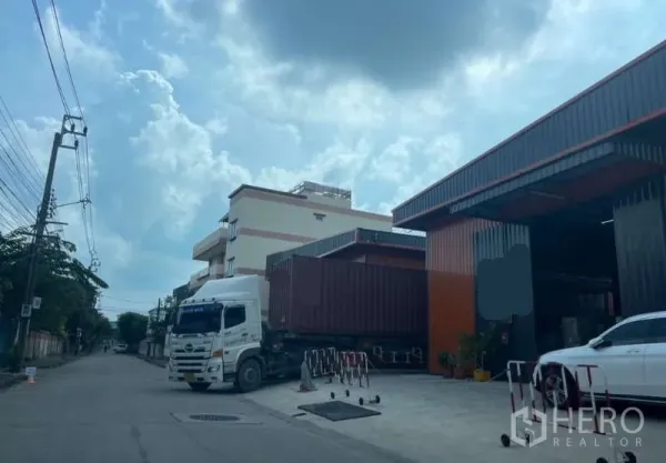 Warehouse for rent in Wang Thonglang, Bangkok - Street-side view of the warehouse compound showing container truck access and an open loading apron.