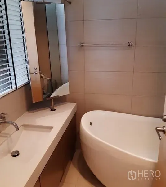 公寓 出租在Khlong Toei, Bangkok - 卫浴间铺瓷砖，设长台盆、镜柜与椭圆形浸泡浴缸。