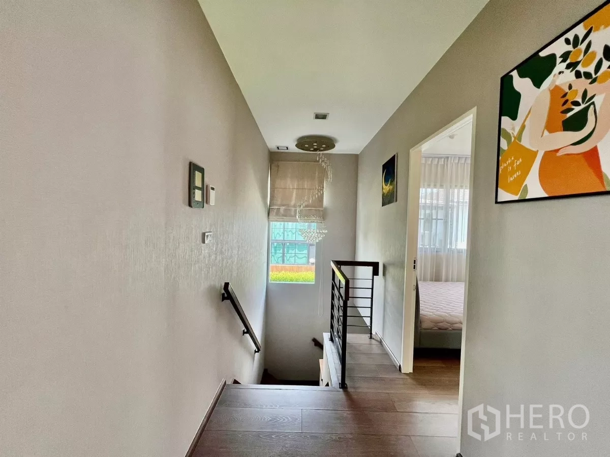 Detached House for rent or sale in Bang Phli, Samut Prakan - Upper hall and staircase with natural light and framed artwork.