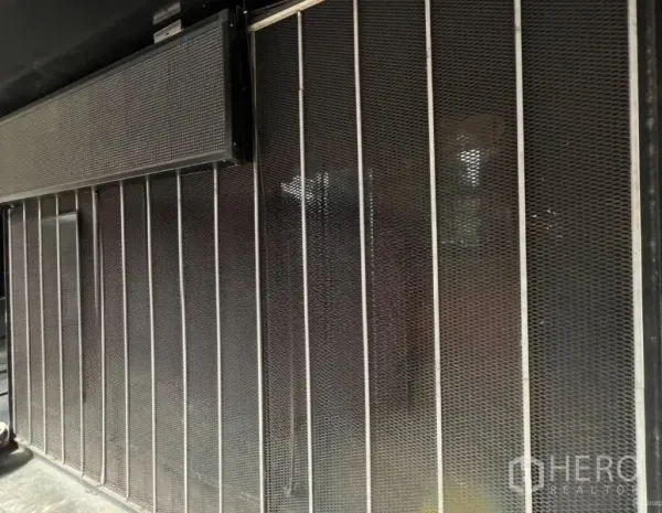 零售空间 出租在Khlong Toei, Bangkok - 曼谷Ekkamai零售铺面外立面，金属网格与滑动安全门的工业风设计。