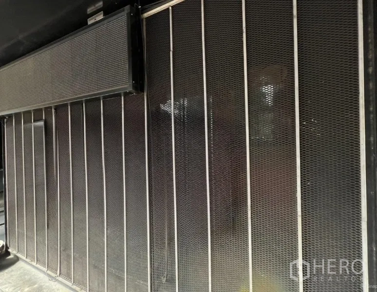 零售空间 出租在Khlong Toei, Bangkok - 曼谷Ekkamai零售铺面外立面，金属网格与滑动安全门的工业风设计。