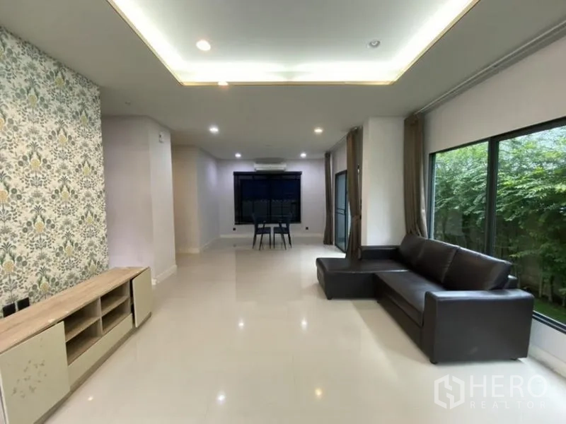 Detached House for rent in Bang Kapi, Bangkok - Spacious living room with recessed lighting, feature wall and sofa seating.