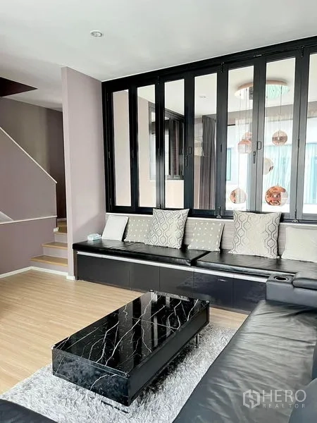 Townhouse for rent in Saphan Sung, Bangkok - Living area with glass partition, built-in bench seating and a staircase.
