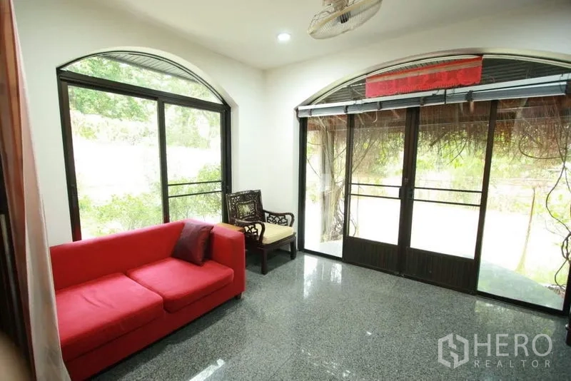 Detached House for rent in Bang Phli, Samut Prakan - Bright sitting room with a red sofa and arched sliding glass doors opening to the garden.