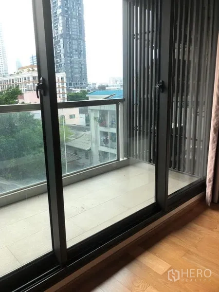 公寓 出售在Bang Rak, Bangkok - 推拉玻璃门通向私人阳台，眺望城市天际线。