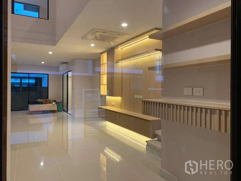 ทาวน์เฮาส์ ให้เช่าหรือขายในSaphan Sung, Bangkok - พื้นที่นั่งเล่นแบบโอเพ่น แผ่นพื้นกระเบื้องเงา ผนังตกแต่งมีไฟ และประตูกระจกบานเลื่อน