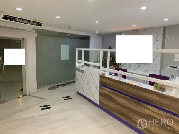 零售空间 出租在Pathum Wan, Bangkok - 接待区设大理石前台、木质细节与玻璃隔断。
