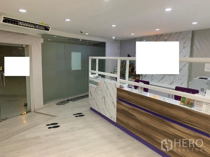 零售空间 出租在Pathum Wan, Bangkok - 接待区设大理石前台、木质细节与玻璃隔断。