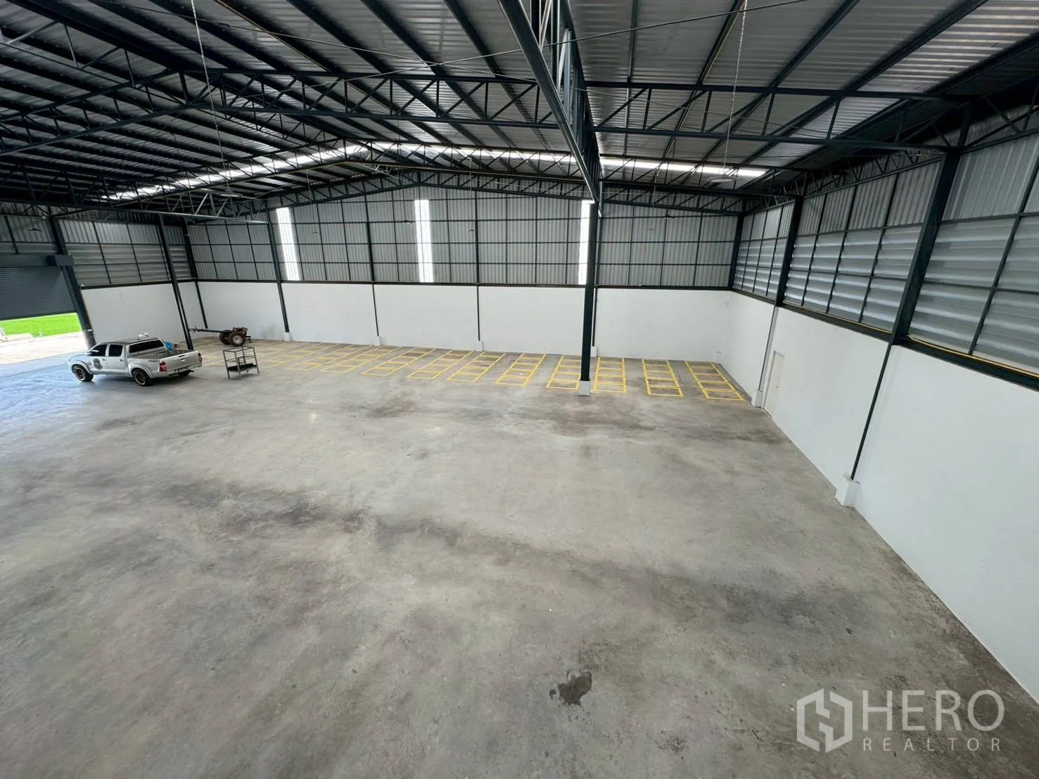 Warehouse for rent in Phutthamonthon, Nakhon Pathom - Aerial view of the warehouse floor showing marked storage bays and a pickup truck.