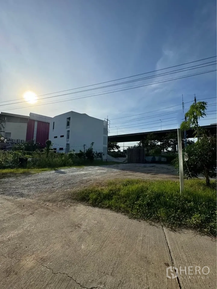 Land for rent in Bang Na, Bangkok - Concrete driveway leading to a level land parcel with perimeter plants and a gate.