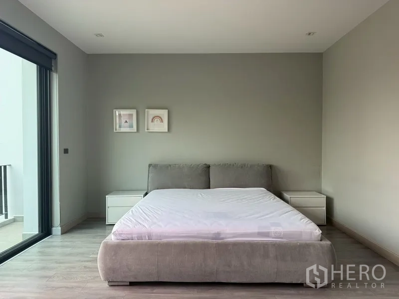 Semi-detached House for rent in Watthana, Bangkok - Minimal bedroom with bed, side tables, and access to a balcony.