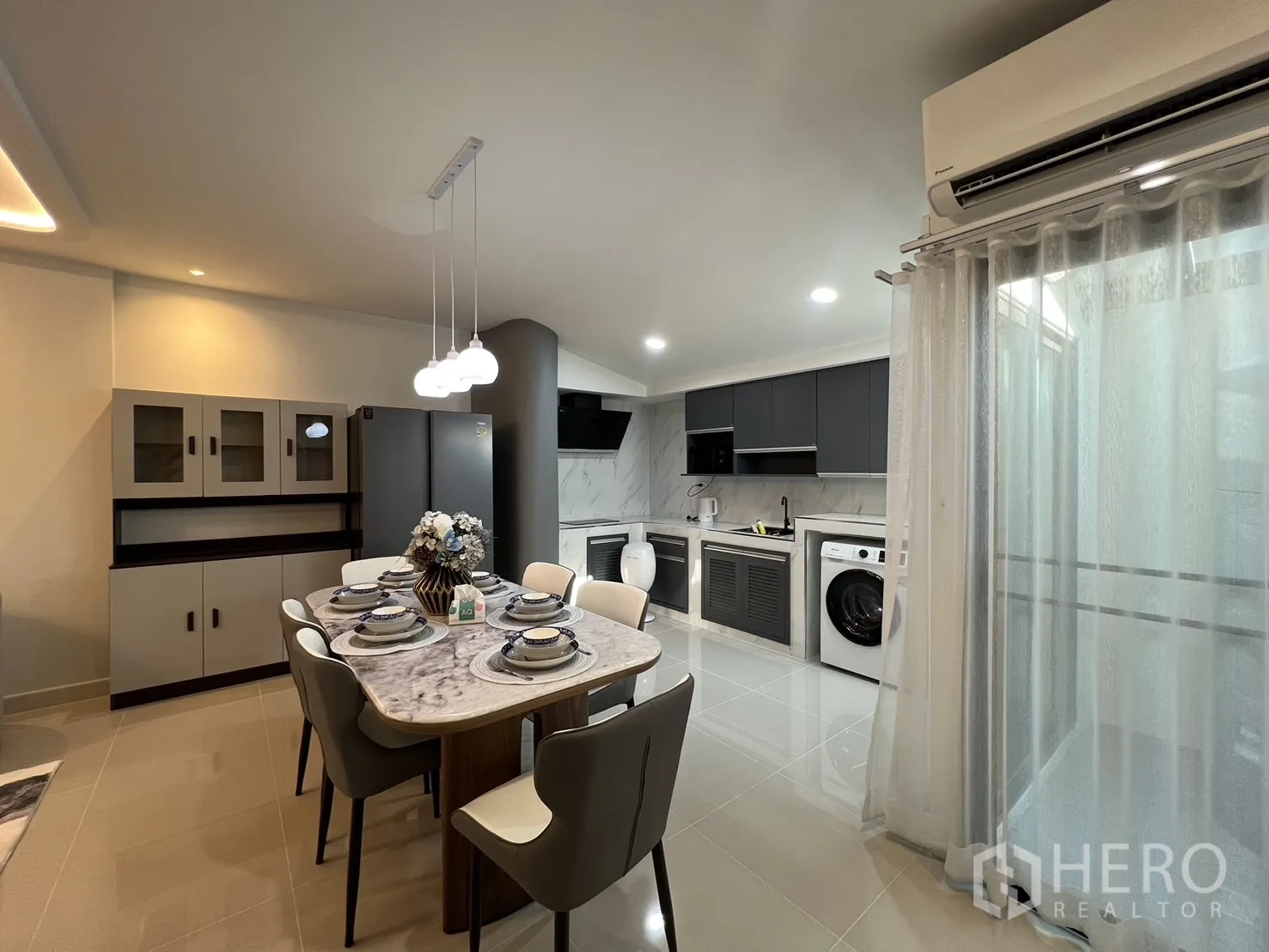 Townhouse for rent in Bang Phli, Samut Prakan - Dining zone with trio pendant lights, air conditioner and floor-to-ceiling curtains.