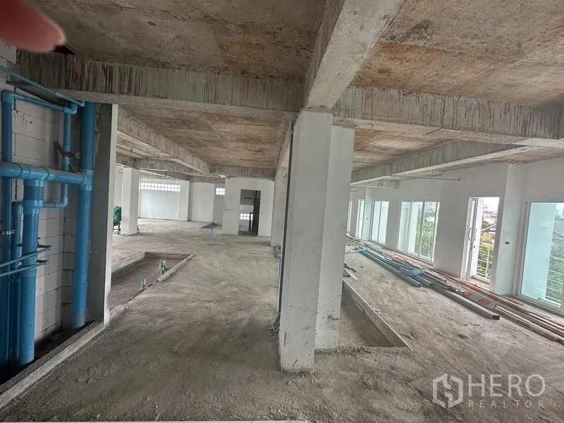 Office Space for rent or sale - Raw concrete floor with exposed columns and blue plumbing lines ready for fit-out.