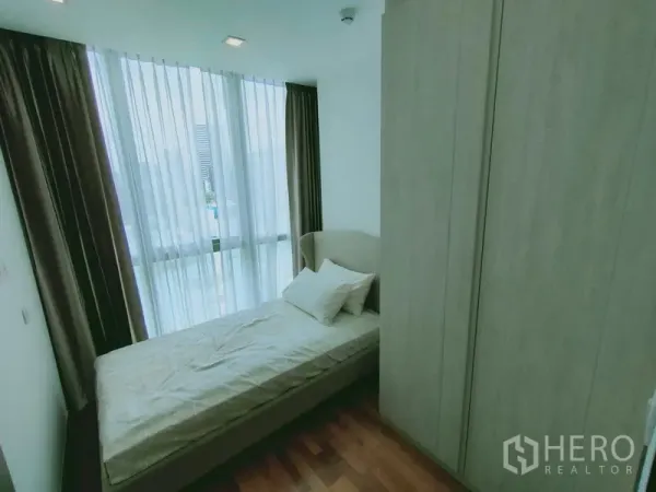 คอนโด ให้เช่าในRatchathewi, Bangkok - ห้องนอนรองมีเตียงเดี่ยว ตู้เสื้อผ้าสูง และหน้าต่างบานใหญ่รับแสงธรรมชาติ.