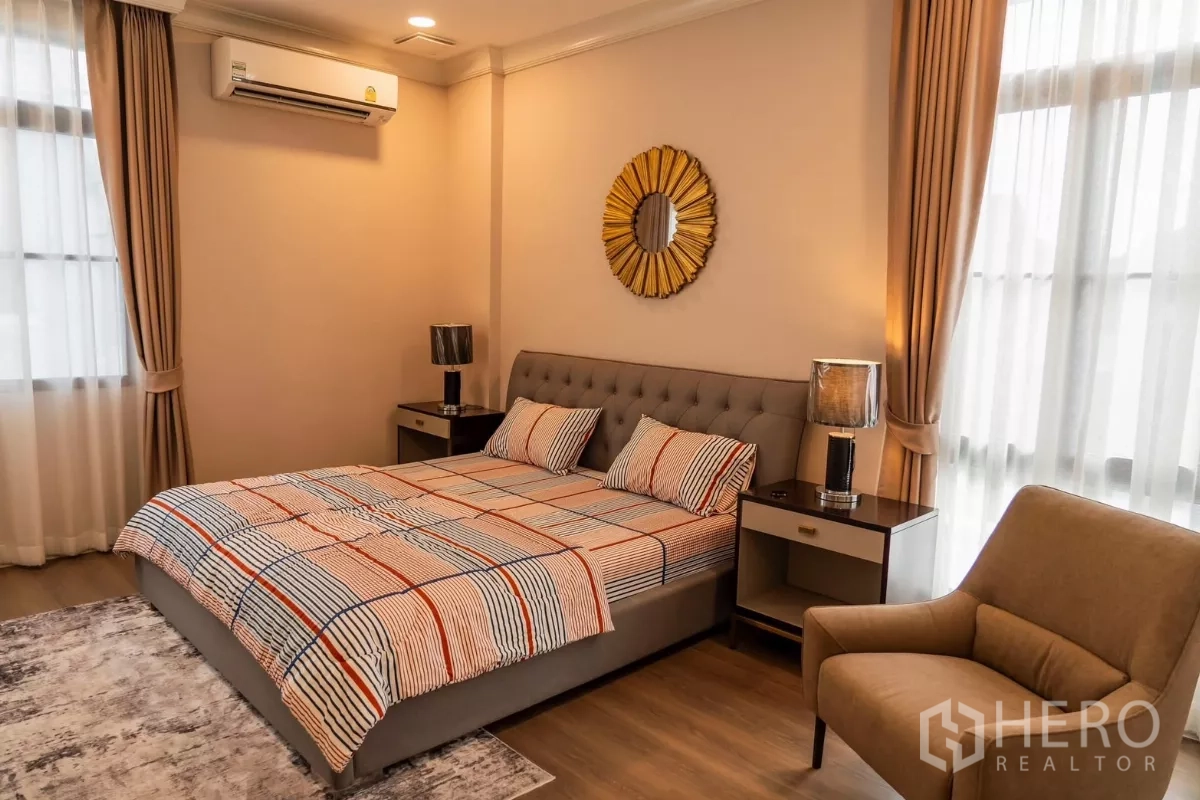 Detached House for rent in Saphan Sung, Bangkok - Guest bedroom with tufted bedhead, patterned bedding and armchair.