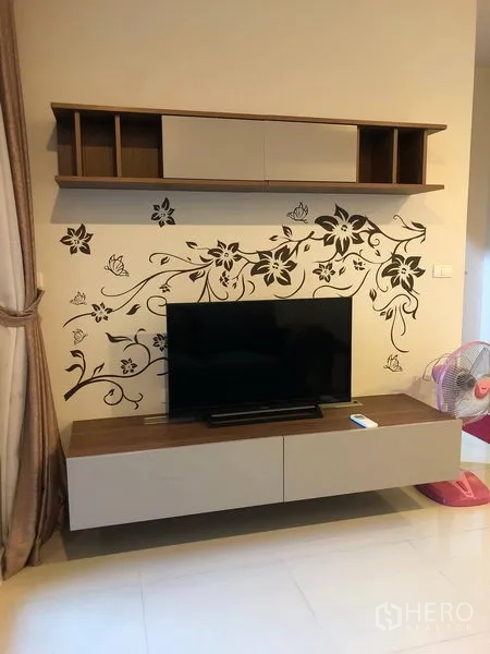 Condominium for sale in Ratchathewi, Bangkok - TV feature wall with floating shelf and floral decal in the living area.