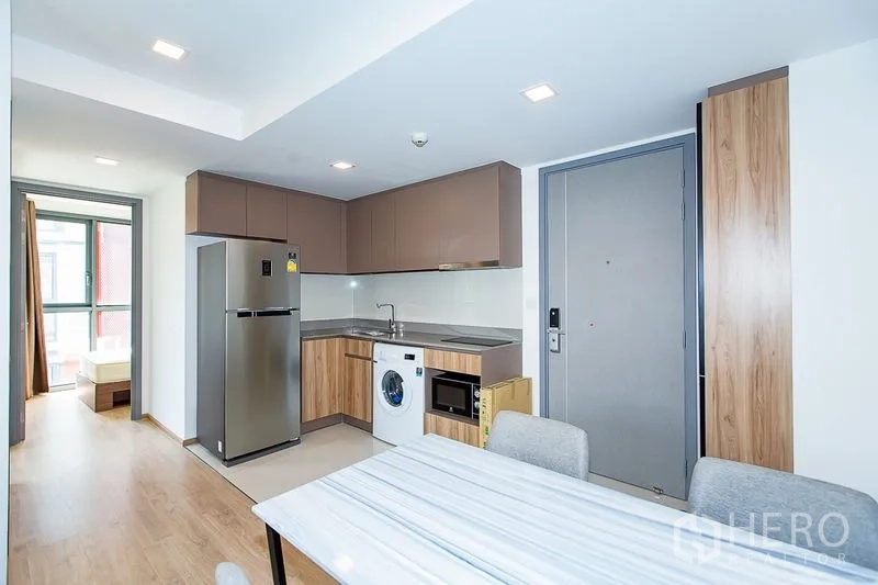 คอนโด ให้เช่าในWatthana, Bangkok - ครัวรูปตัวแอลพร้อมตู้เก็บของ ซิงก์สแตนเลส เครื่องซักผ้า ไมโครเวฟ และตู้เย็นสูงติดประตู