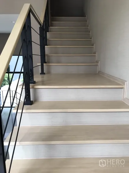 ทาวน์เฮาส์ ขายในSuan Luang, Bangkok - ภาพระยะใกล้ของบันไดไม้กับเสาเหล็ก และผนังโทนกลาง