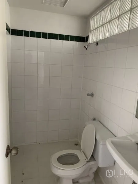 店屋 出租在Bang Na, Bangkok - 整洁的瓷砖卫浴，配坐便器、洗手盆与玻璃砖采光窗。