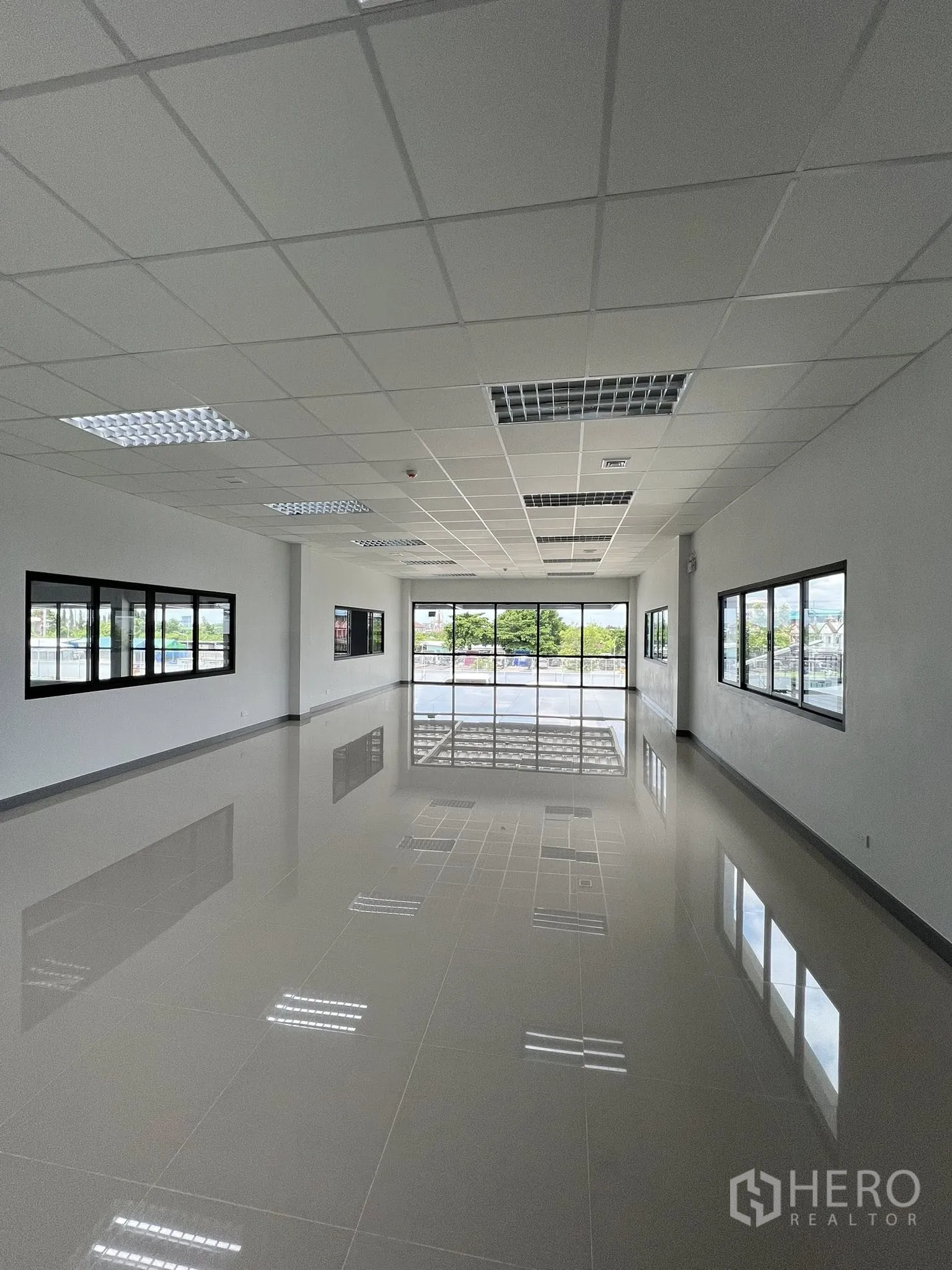 Warehouse for rent in Phra Pradaeng, Samut Prakan - Long upstairs office room with tiled floor, grid ceiling and wide windows.