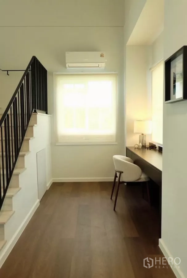 Detached House for rent in Bang Phli, Samut Prakan - Upstairs landing with built-in work desk, chair and window beside a black metal stair rail.
