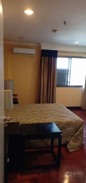 คอนโด ให้เช่าในWatthana, Bangkok - ห้องนอนอบอุ่นพร้อมชุดเครื่องนอนลายโต๊ะข้างเตียง หน้าต่างผ้าม่านสีน้ำตาล และแอร์แขวนผนัง