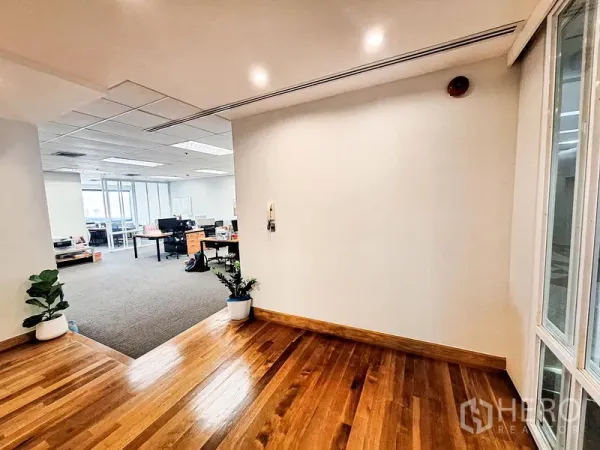 办公空间 出租在Bang Na, Bangkok - 入口前厅采用亮面木地板，通向铺地毯的开放式办公区，并摆放绿植。