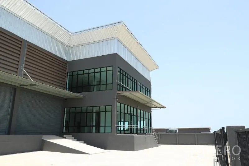 Factory for rent or sale in Bang Bo, Samut Prakan - Modern factory corner in Bang Bo, Samut Prakan with glass-front office, canopy and loading ramp.