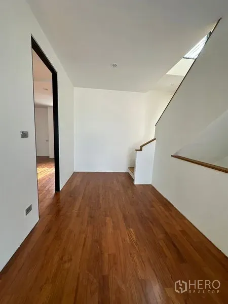 独立式住宅 出租在Watthana, Bangkok - 楼上过道铺木地板，白色墙面与楼梯，空间明亮通透。