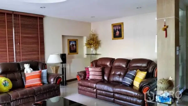 Detached House for sale in Suan Luang, Bangkok - Cozy living room with leather sofas, colorful cushions, blinds and neutral decor.