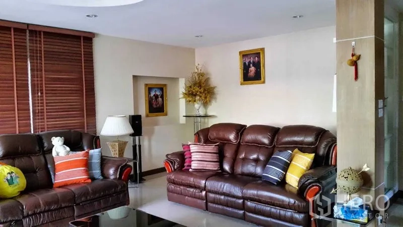 Detached House for sale in Suan Luang, Bangkok - Cozy living room with leather sofas, colorful cushions, blinds and neutral decor.
