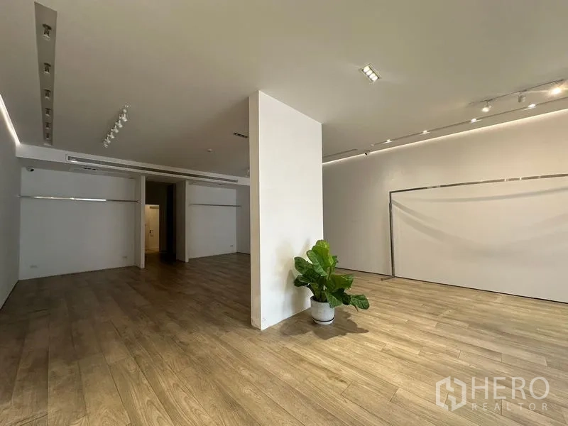 สำนักงานที่บ้าน ให้เช่าในPhra Khanong, Bangkok - ฮอลล์กว้าง มีเสากลาง ต้นไม้ตกแต่ง และพื้นไม้โทนอุ่น พร้อมสปอตไลท์