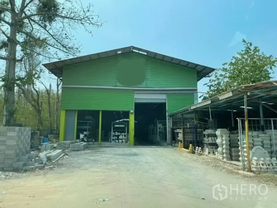 Warehouse for rent in Phra Samut Chedi, Samut Prakan - Green metal-clad warehouse exterior with open bays and storage yard.