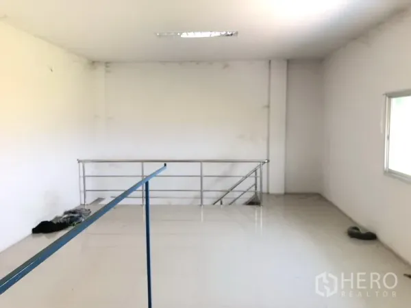 Factory for rent in Pathum Thani - Bright mezzanine office space with tiled floor, side window and metal stair railing inside the factory.