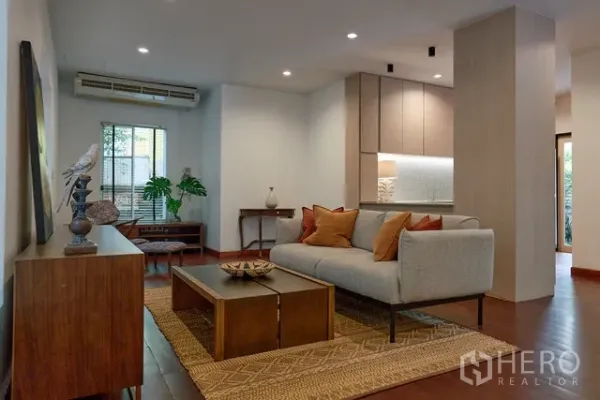 บ้าน ให้เช่าในWatthana, Bangkok - ห้องนั่งเล่นโทนอุ่นพร้อมโซฟา พรม และครัวบิลท์อิน ใต้ไฟดาวน์ไลท์และพื้นไม้