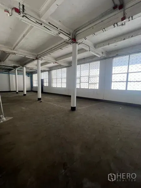 Shophouse for rent in Samphanthawong, Bangkok - Bright upper floor with large grid windows, exposed ceiling and support columns.