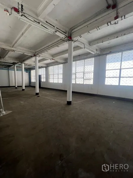 Shophouse for rent in Samphanthawong, Bangkok - Bright upper floor with large grid windows, exposed ceiling and support columns.