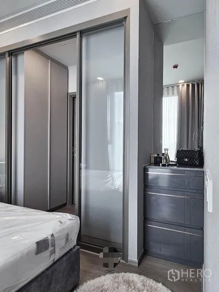 Condominium for rent in Samut Prakan - Bedroom corner with sliding wardrobes and a vanity mirror.