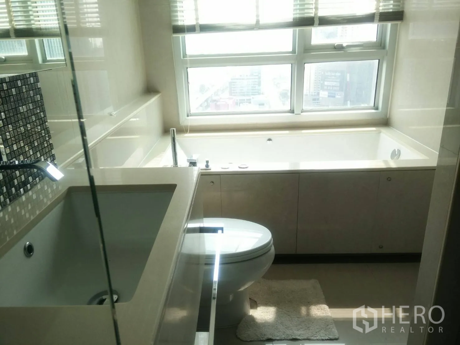 Condominium for rent in Ratchathewi, Bangkok - Modern bathroom with large window-side soaking bathtub, toilet and vanity with mosaic backsplash