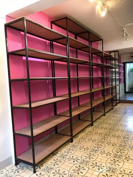 零售空间 出租在Khlong Toei, Bangkok - 整面墙安装工业风金属货架，粉色背景与轨道灯照明。