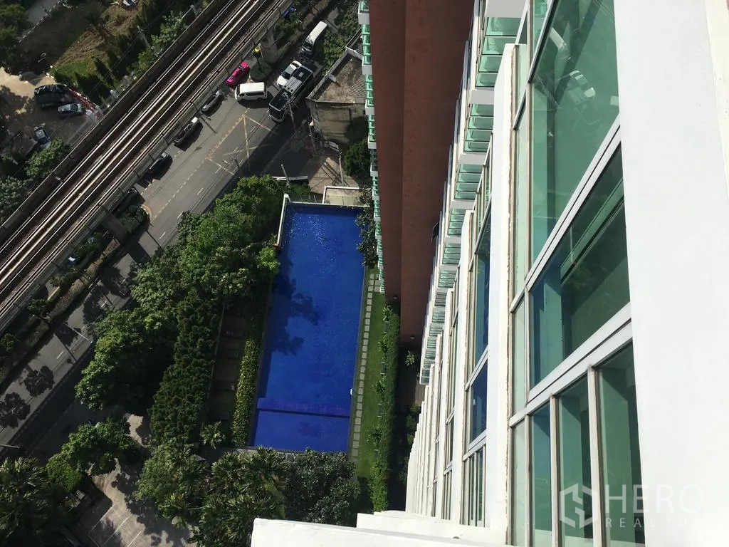 Condominium for rent in Watthana, Bangkok - High-floor view of outdoor lap pool, gardens and BTS tracks below.