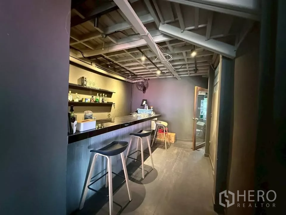 零售空间 出租在Watthana, Bangkok - 室内吧台区域，配高脚椅、墙面置物架和轨道灯