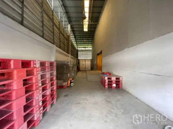 Warehouse for rent in Bueng Kum, Bangkok - Covered loading bay with stacked pallets and access to storage and dock area for trucks.
