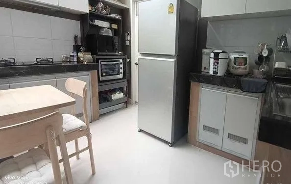 Detached House for rent in Don Mueang, Bangkok - Fitted kitchen with gas hob, ample cabinets, refrigerator and a compact breakfast table.