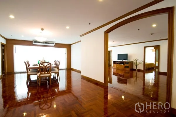 房间 出租在Khlong Toei, Bangkok - 开放式餐客厅，拱形门洞，餐桌与电视柜，木地板光亮如新。